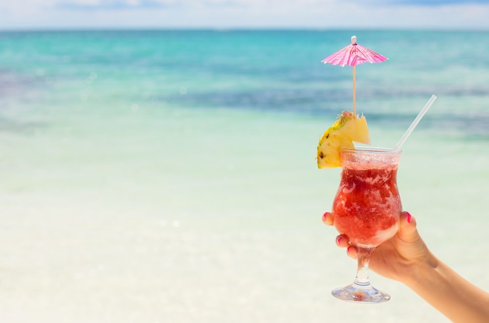 Tropical drink being held on a beach in the Caribbean